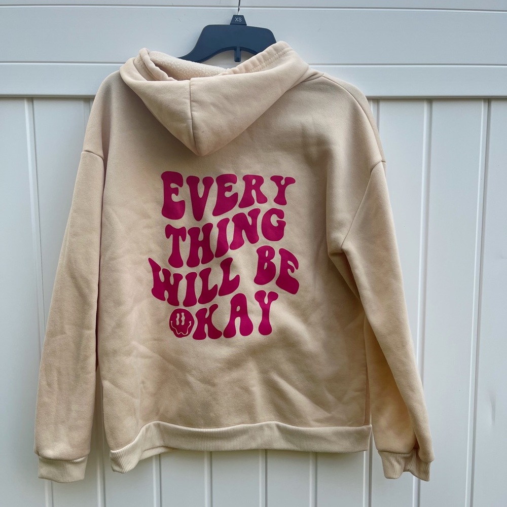 Trendy tan sweatshirt with pink saying of “everything will be okay” on the back